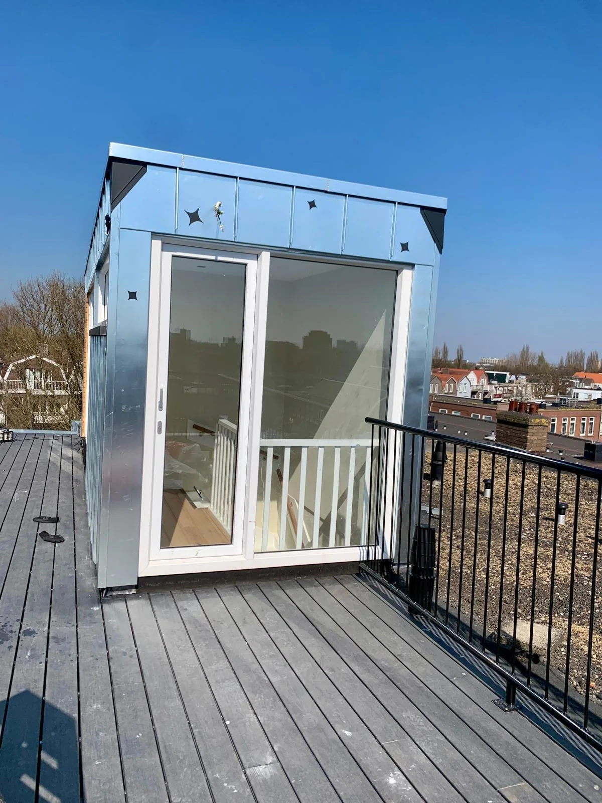 Metalen dakopbouw met glazen deur aan een dakterras.