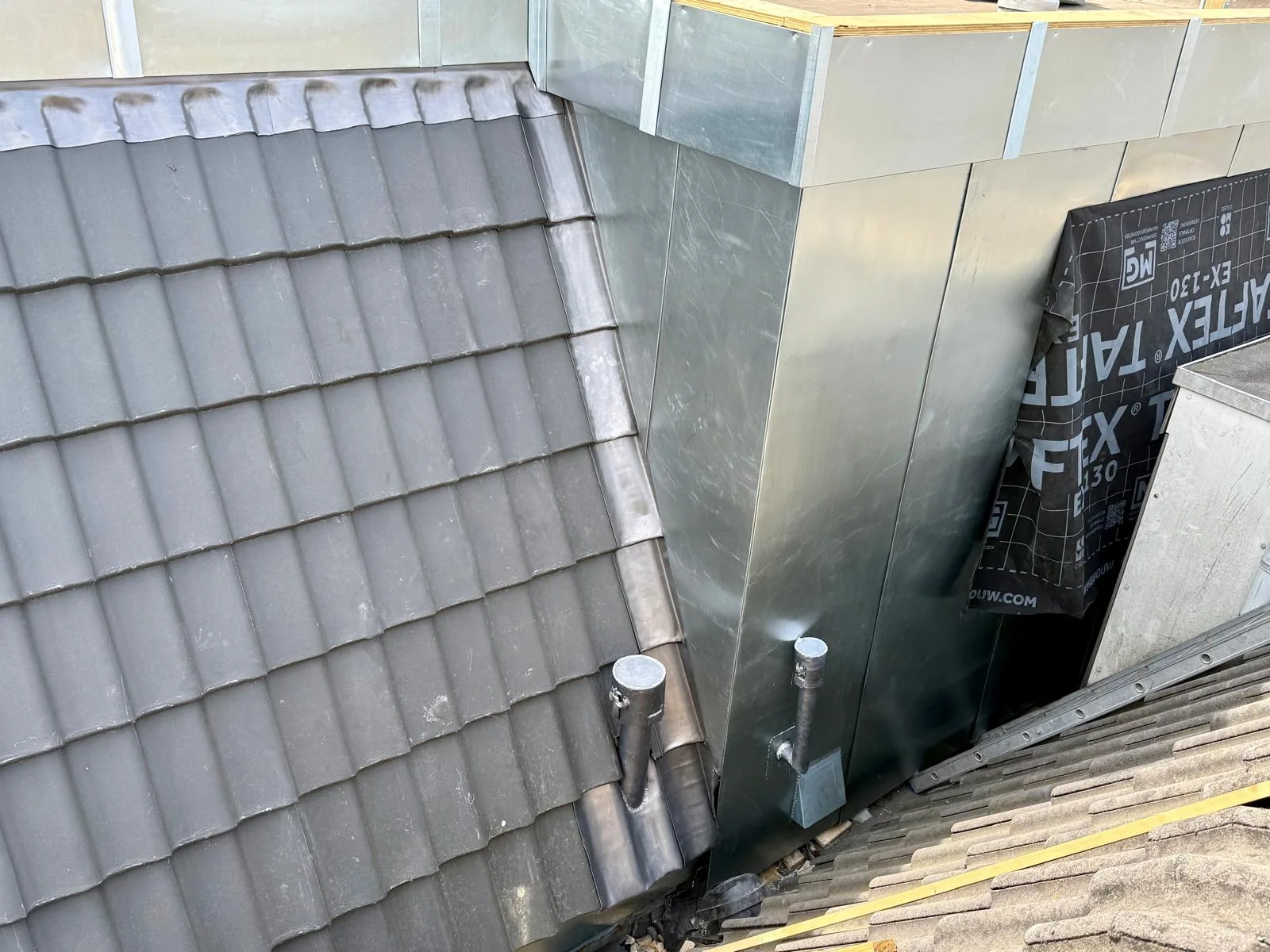 Metalen dakopbouw tussen twee hellende dakvlakken tijdens het werk.